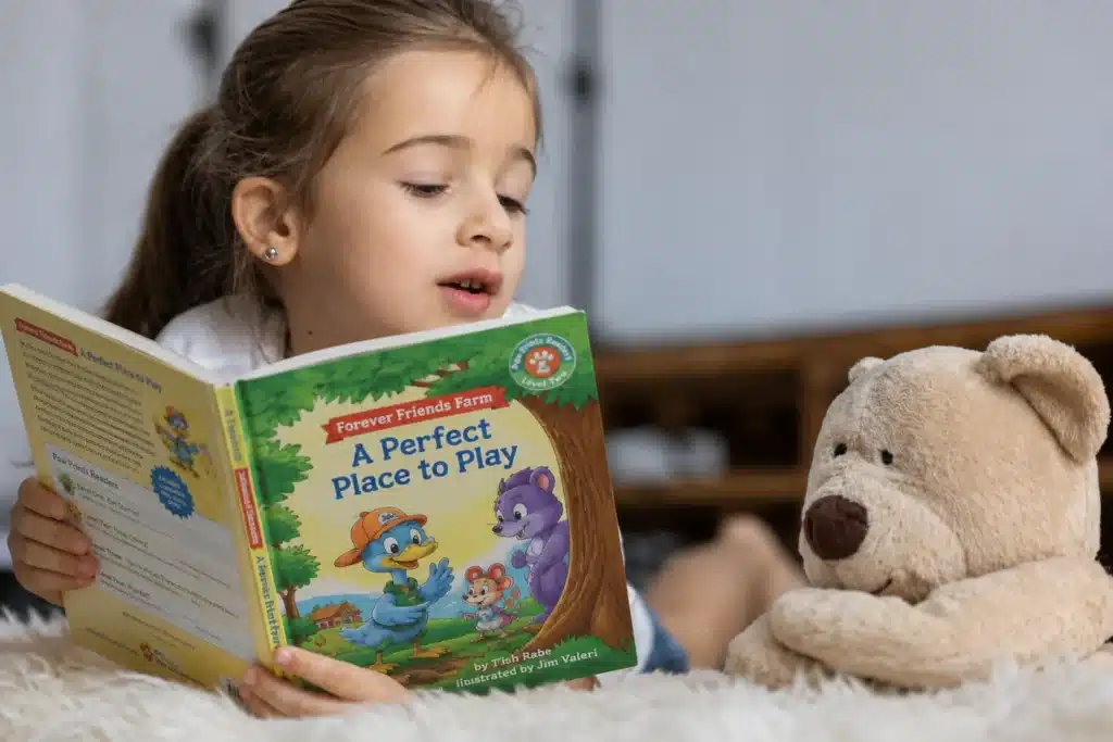 Child reading A Perfect Place to Play beside a teddy bear